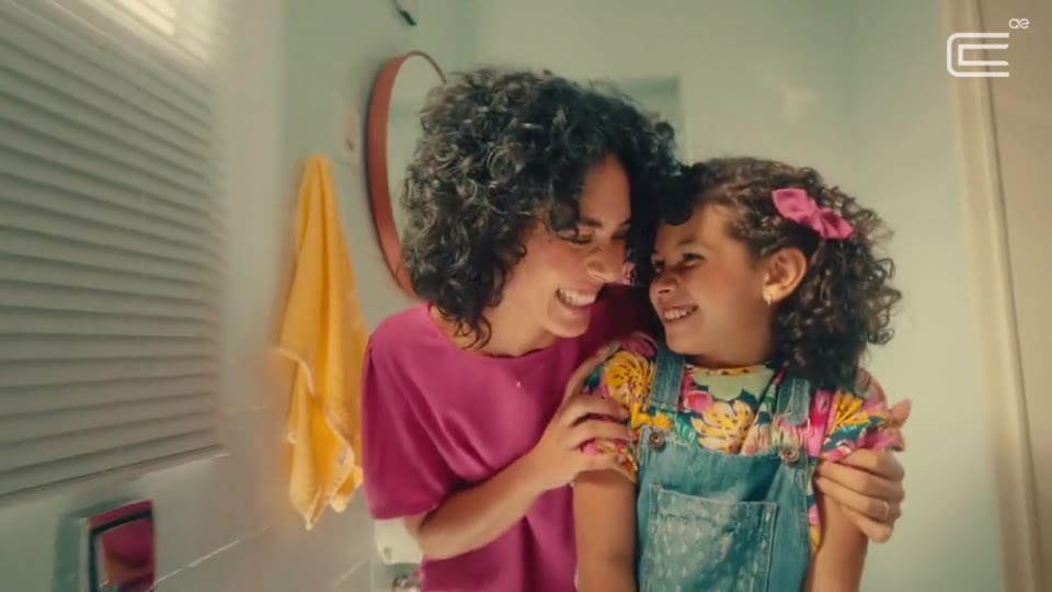 Mãe e filha se abraçam sorrindo no banheiro de casa, frame do filme da Corsan